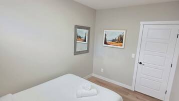 A bedroom with a single bed, a door, and two framed pictures on the wall.