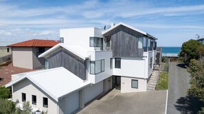 Ein modernes, mehrstöckiges Gebäude mit flachem Dach, großen Fenstern und Blick auf das Meer.