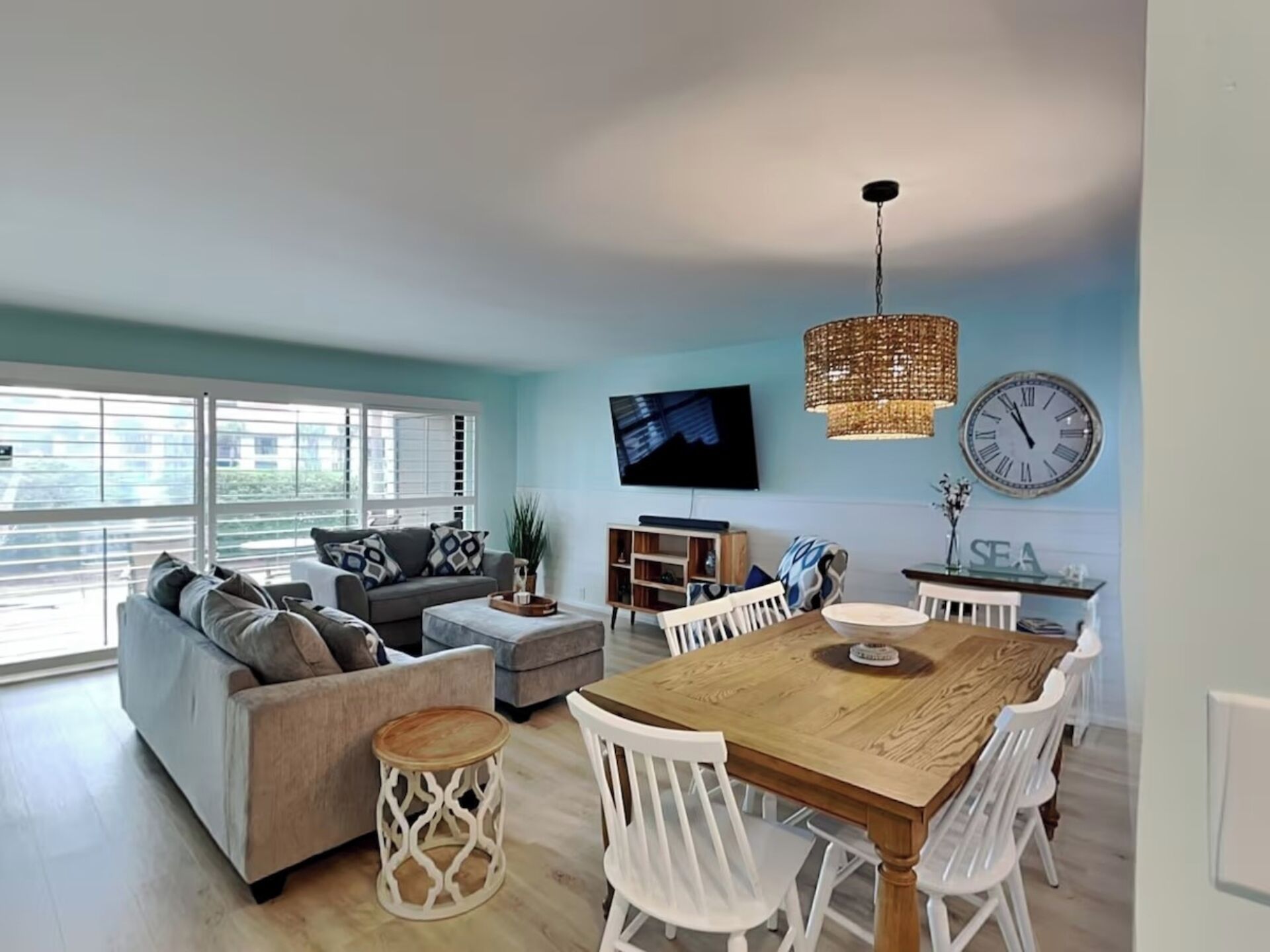 A modern living room with a sofa, ottoman, and dining table with chairs.