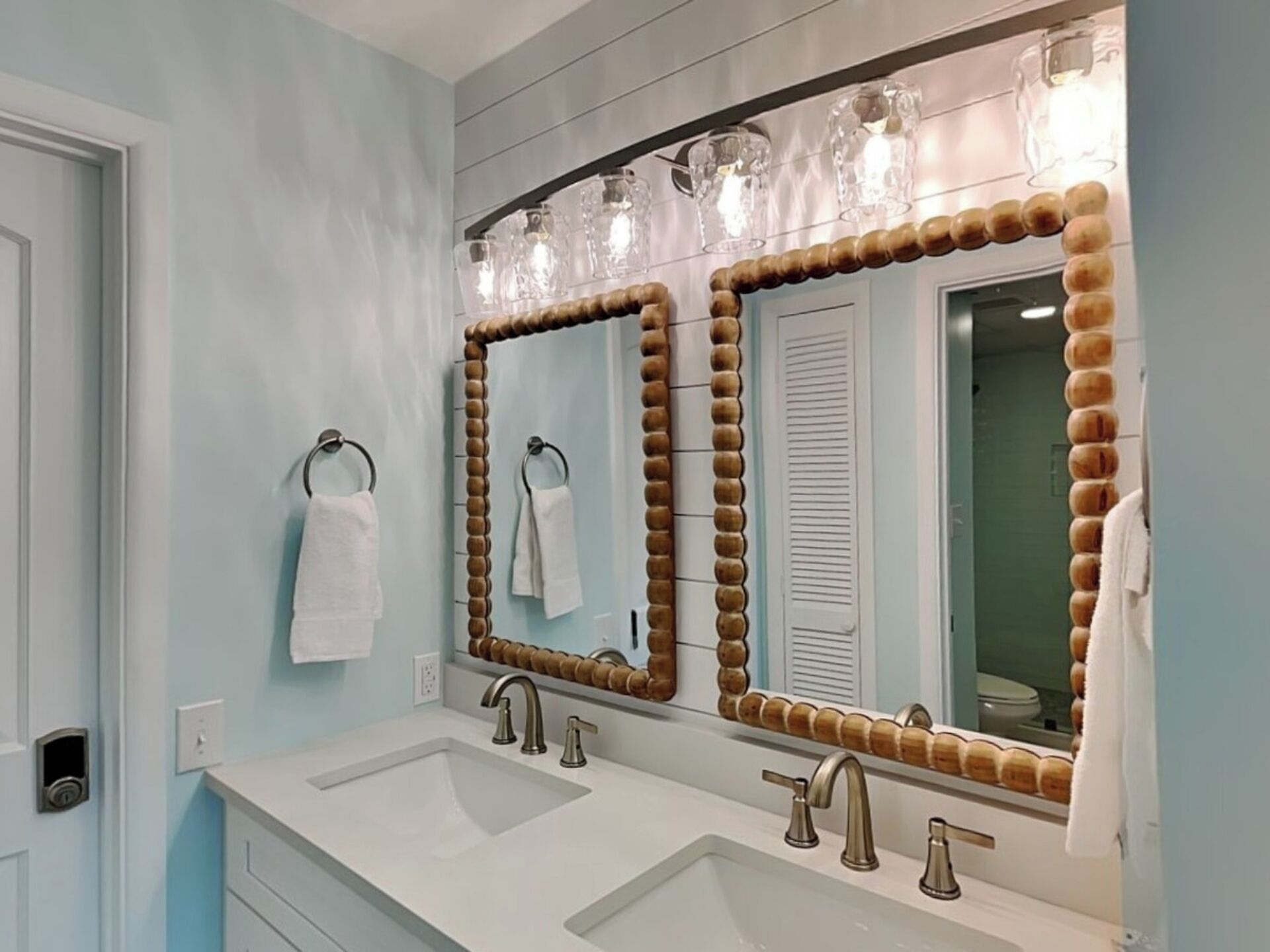 Un baño con dos lavamanos, un espejo de marco de madera y un perchero para toallas.