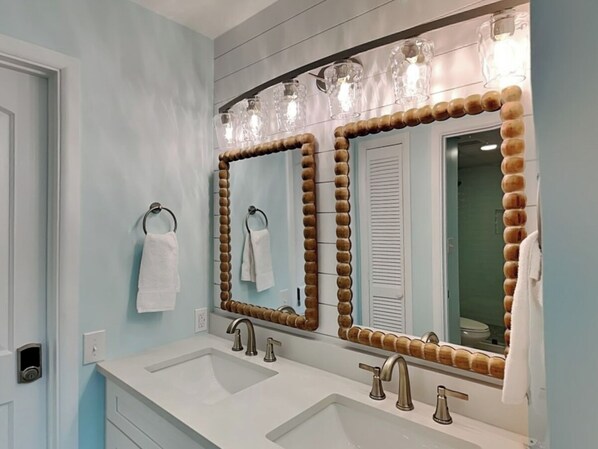 Ein Badezimmer mit zwei Waschbecken, einem Spiegel mit Holzrahmen und einem Handtuchhalter.