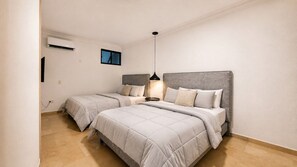 Habitació d'hotel amb dos llits, un penjol i un aparell d'aire condicionat.