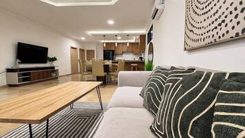 A modern living room with a sofa, a wooden coffee table, and a flat-screen TV.