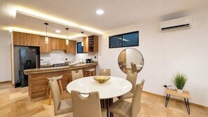 Une cuisine moderne avec un îlot central, un coin repas avec des chaises et un grand miroir rond.