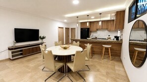 A modern kitchen with a dining area, a flat-screen TV, and a large mirror. - Stylish Kennedy Norte | Near Parque Lineal (Guayaquil)
