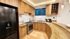 Eine moderne Küche mit Holzausbau, einem Edelstahlkühlschrank, einem Gasherd und einem Einbauofen.