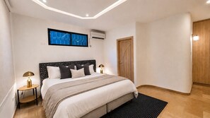 Une chambre à coucher avec un lit, des tables de chevet, une fenêtre et une porte.
