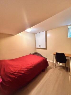 Ein Schlafzimmer mit einem Einzelbett, einem Schreibtisch und einem Stuhl.