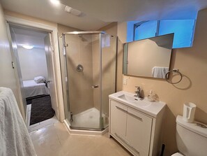 Ein Badezimmer mit Duschkabine, Waschbecken, Toilette und Spiegel.