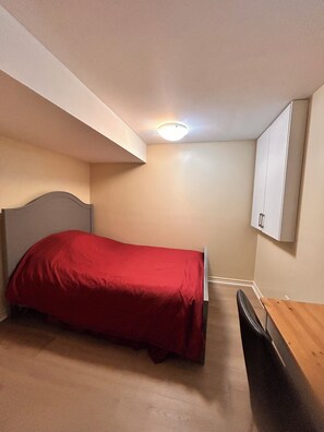 Ein Schlafzimmer mit einem Einzelbett, einem Schreibtisch und einem Kleiderschrank.