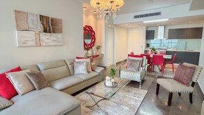 A modern living room with a sofa, armchairs, a coffee table, and a dining area with red chairs and a kitchen in the background. - Amazing experience with ocean views on Balboa Ave 2 (Panamá)