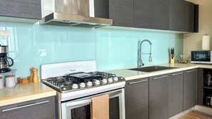 A modern kitchen with a gas stove, a microwave, and a sink. - Amazing experience with ocean views on Balboa Ave 2 (Panamá)