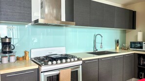A modern kitchen with a gas stove, a microwave, and a sink. - Amazing experience with ocean views on Balboa Ave 2 (Panamá)