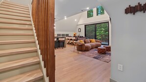 A modern interior with a staircase, a dining area, and a living space with a large window. - AlpenDorf A-Frame— new! one-of-a-kind luxury a-frame, dog friendly, natural creek, mins from Helen (Sautee Nacoochee)