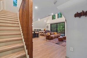 A modern interior with a staircase, a dining area, and a living space with a large window. - AlpenDorf A-Frame— new! one-of-a-kind luxury a-frame, dog friendly, natural creek, mins from Helen (Sautee Nacoochee)
