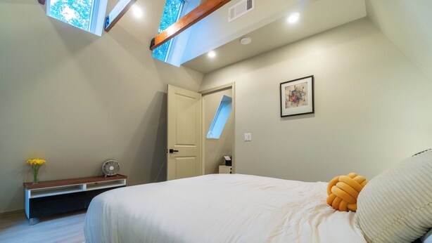 A bedroom with a bed, a bedside table with a fan, a window, and a door. - AlpenDorf A-Frame— new! one-of-a-kind luxury a-frame, dog friendly, natural creek, mins from Helen (Sautee Nacoochee)