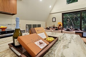 A modern kitchen with a marble countertop, a bottle of wine, and a box labeled 'Travel'. - AlpenDorf A-Frame— new! one-of-a-kind luxury a-frame, dog friendly, natural creek, mins from Helen (Sautee Nacoochee)