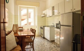 A compact kitchen with a dining area, a refrigerator, and a microwave. - Sun and Sea - Alghero (Alghero)