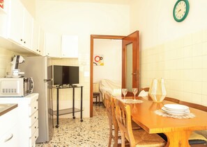 Cozinha compacta com micro-ondas, fogão e uma televisão sobre uma mesa pequena.
