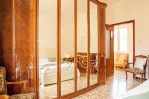 A hotel room with a large mirror, a bed with a white comforter, a wooden chair, and a small table with a lamp. - Sun and Sea - Alghero (Alghero)