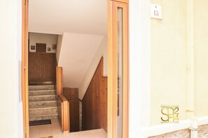 A staircase leading to an upper floor with wooden railings and a white wall with a number sign. - Sun and Sea - Alghero (Alghero)
