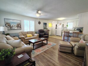 A living room with a sofa, armchairs, a coffee table, and a dining area with a kitchen in the background. - " Tiny Getaway " 2 Bedrooms 1 Bath Home (Supply)