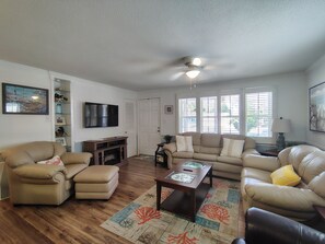 A living room with a sofa set, a coffee table, and a TV mounted on the wall. - " Tiny Getaway " 2 Bedrooms 1 Bath Home (Supply)