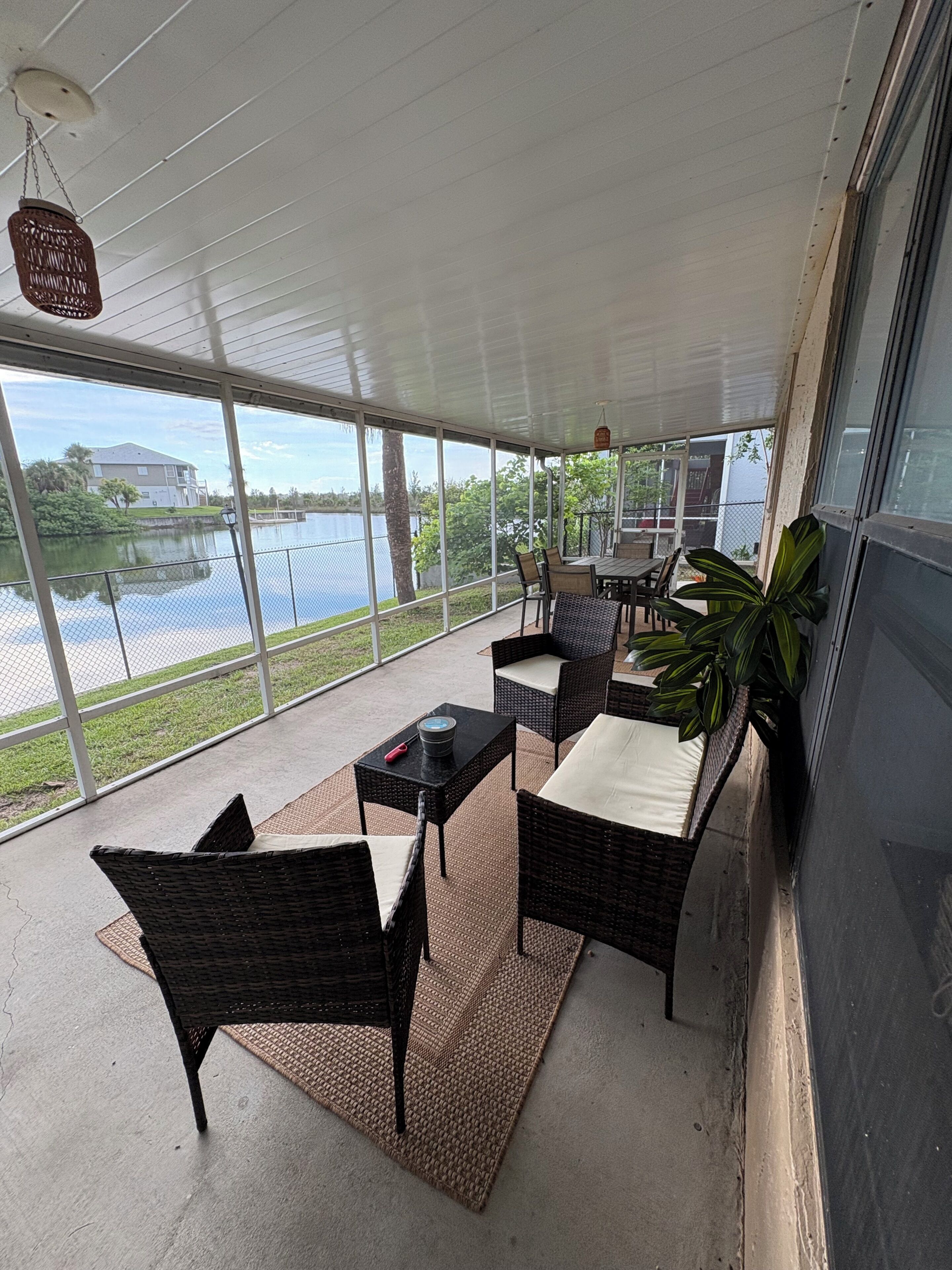 A covered patio with wicker furniture, a table with a record player, and a view of a lake.