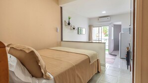 Quarto de hotel com cama, mesa de cabeceira, espelho e janela.