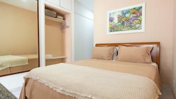 Un dormitorio con cama, armario, espejo y un cuadro en la pared.