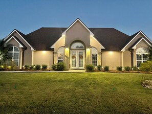 A two-story house with a symmetrical facade, a central entrance with a decorative arch, and a well-maintained lawn.