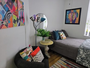 A modern living room with a sofa, armchair, and a small round table with a plant. - Chic One‑Bedroom Manhattan Apartment on Historic Strivers Row (New York)