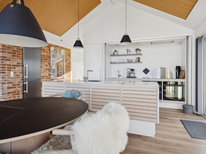 Een moderne keuken met een centraal eiland, hanglampen en een accentmuur van baksteen.
