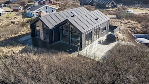 Een modern huis met een grote glazen gevel, een schuin dak en een terras.