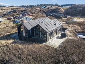 A modern house with a large glass facade, a sloped roof, and a deck. - "Nuka" - 250m from the sea by Interhome (Hjørring)