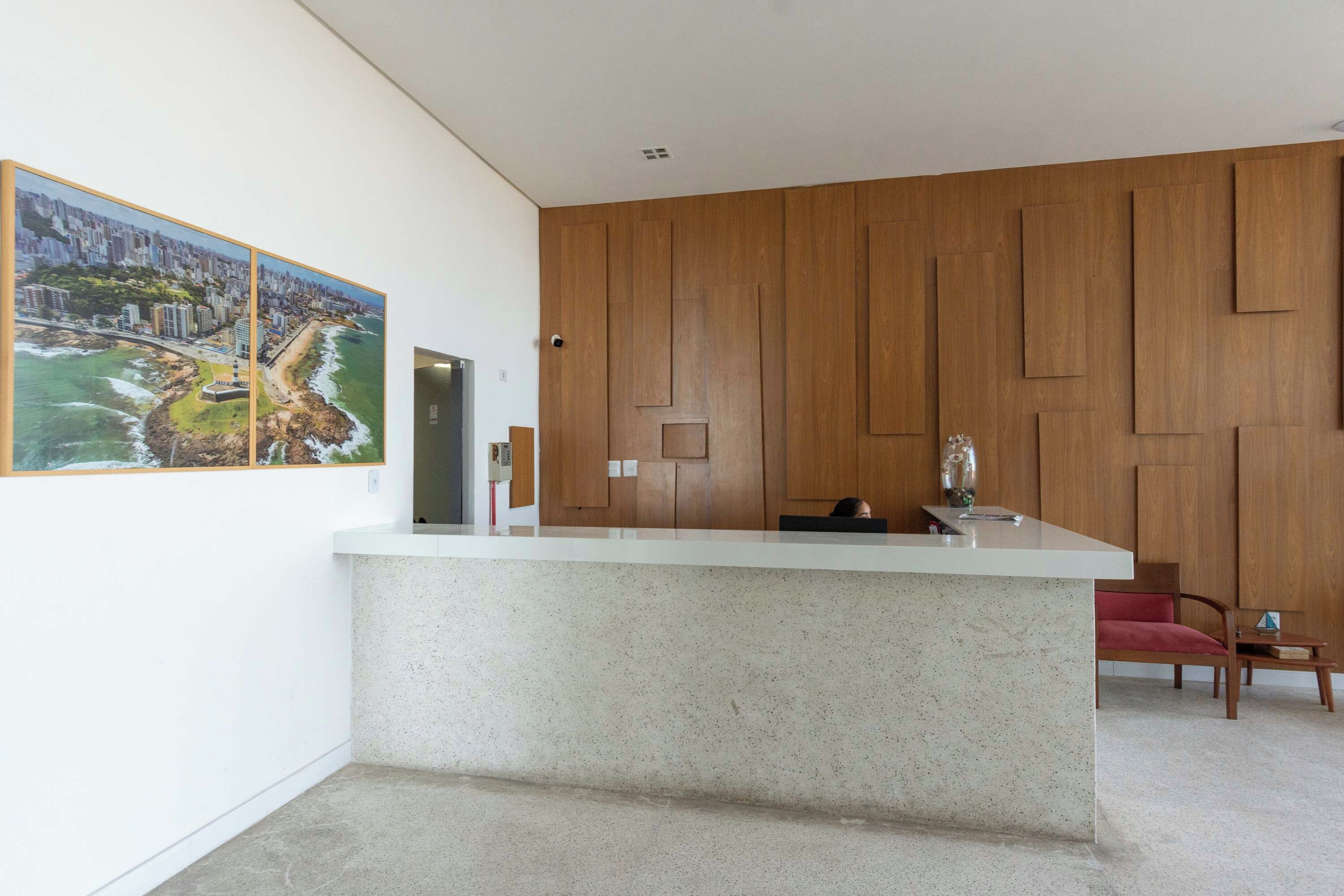 A modern reception area with a marble counter, wooden panel wall, and a cityscape painting.