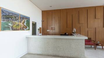 A modern reception area with a marble counter, wooden panel wall, and a cityscape painting.