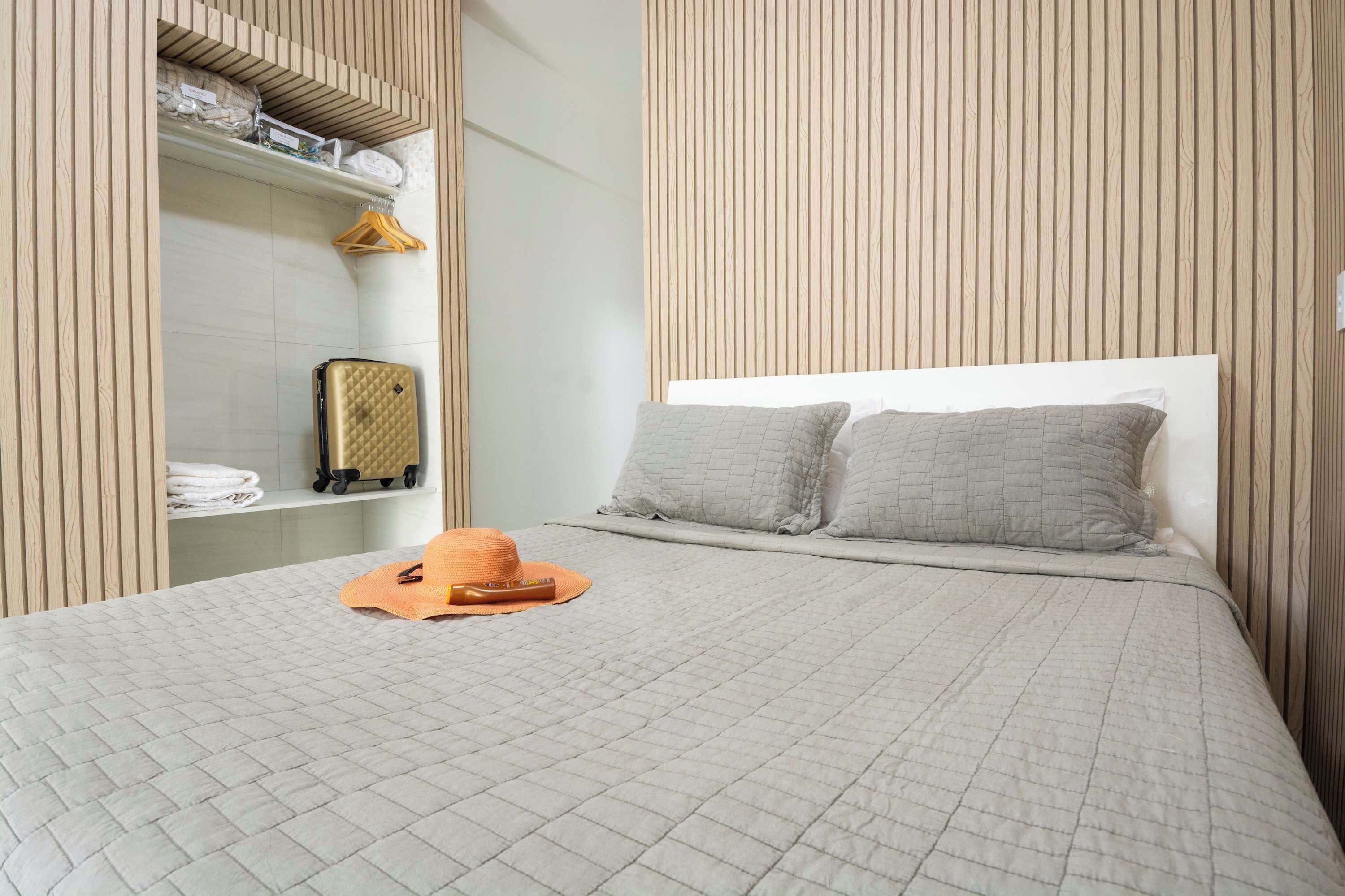 Une chambre d’hôtel comprenant un lit, une armoire et une étagère avec des serviettes et des articles de toilette.