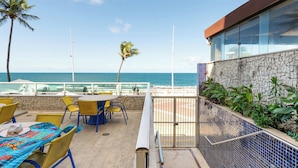 Terraço com vista para o oceano, com área de estar ao ar livre e muro de pedra.