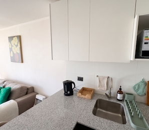 Eine moderne Küche mit einer Granit Arbeitsplatte, einer Kaffeemaschine, einem gewebten Korb und einem Spülbecken mit Seifenspender.