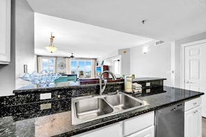 A modern kitchen with a double sink, granite countertops, and a view of the living area. - Gulf Views~Seascape Resort~Large Condo~ARD1701 (Miramar Beach)