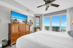 A hotel room with a large bed, a ceiling fan, a TV on a wooden cabinet, and a balcony with a view of the ocean. - Gulf Views~Seascape Resort~Large Condo~ARD1701 (Miramar Beach)