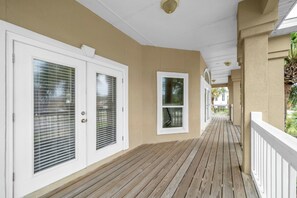 A covered wooden deck with white railings and beige walls. - Joy by the Sea large home w/ harbor views pet friendly private dock (Destin)