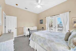 A bedroom with a bed, a crib, a radiator, a ceiling fan, and a view of the outside. - Joy by the Sea - Large Home w/ Harbor Views - Pet Friendly & Private Dock (Destin)