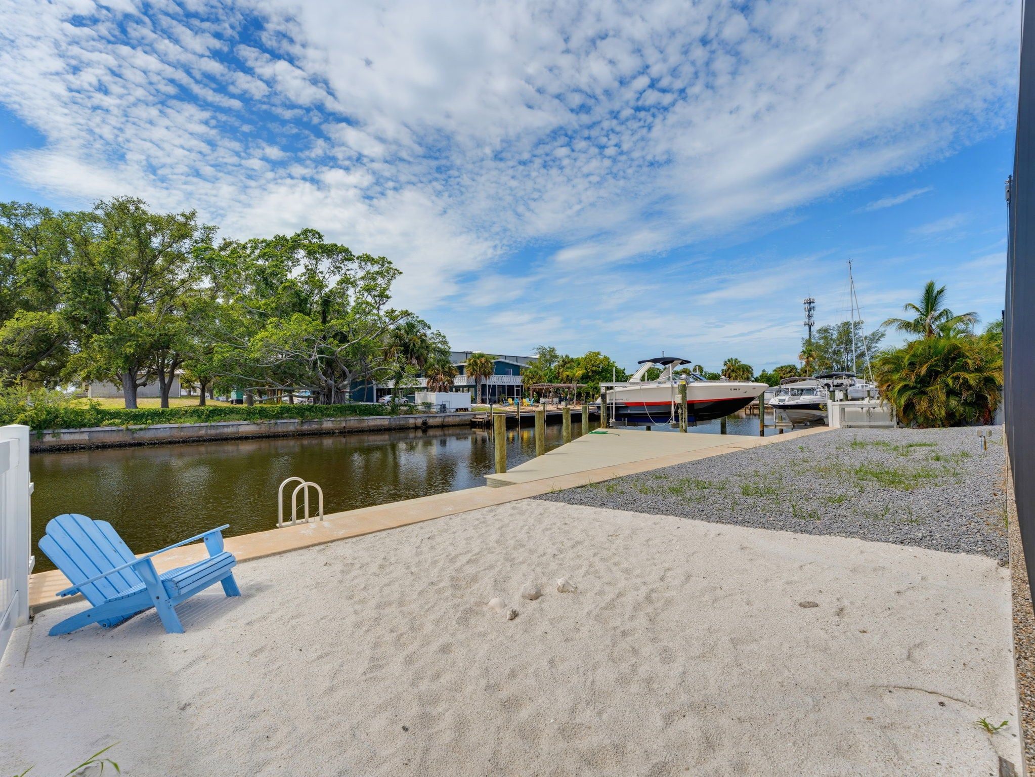 A waterfront property with a sandy beach, a dock, and a boat.