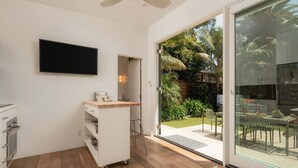 A modern kitchen with a flat-screen TV, a built-in oven, and a small countertop with a coffee maker. - A Mesa Gem with Chic Coastal Vibes, Lush Outdoor Space, Detached Guest Studio & Hot Tub! (Santa Barbara)