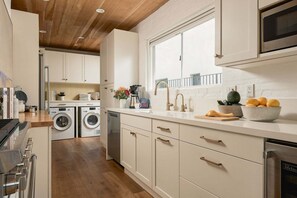 A modern kitchen with built-in appliances, a large window, and a view of the outdoors. - A Mesa Gem with Chic Coastal Vibes, Lush Outdoor Space, Detached Guest Studio & Hot Tub! (Santa Barbara)