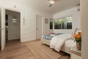 Ein Schlafzimmer mit Bett, Fenster, Tür und Deckenventilator.