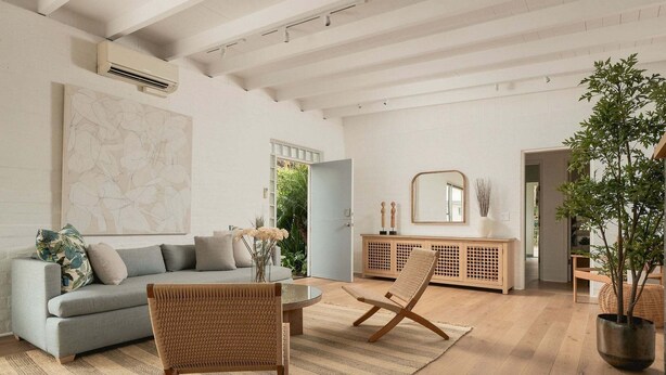 A spacious living room with a grey sofa, two wicker chairs, a wooden cabinet, and a large mirror. - A Mesa Gem with Chic Coastal Vibes, Lush Outdoor Space, Detached Guest Studio & Hot Tub! (Santa Barbara)