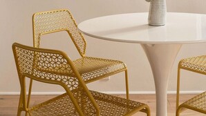 A dining area with a round table, two chairs with a woven design, and two wall-mounted artworks. - A Mesa Gem with Chic Coastal Vibes, Lush Outdoor Space, Detached Guest Studio & Hot Tub! (Santa Barbara)